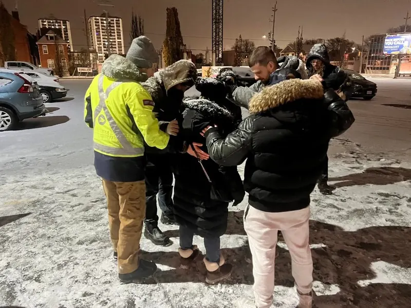 Love on Hamilton outreach team praying with people on a snowy Hamilton street at night